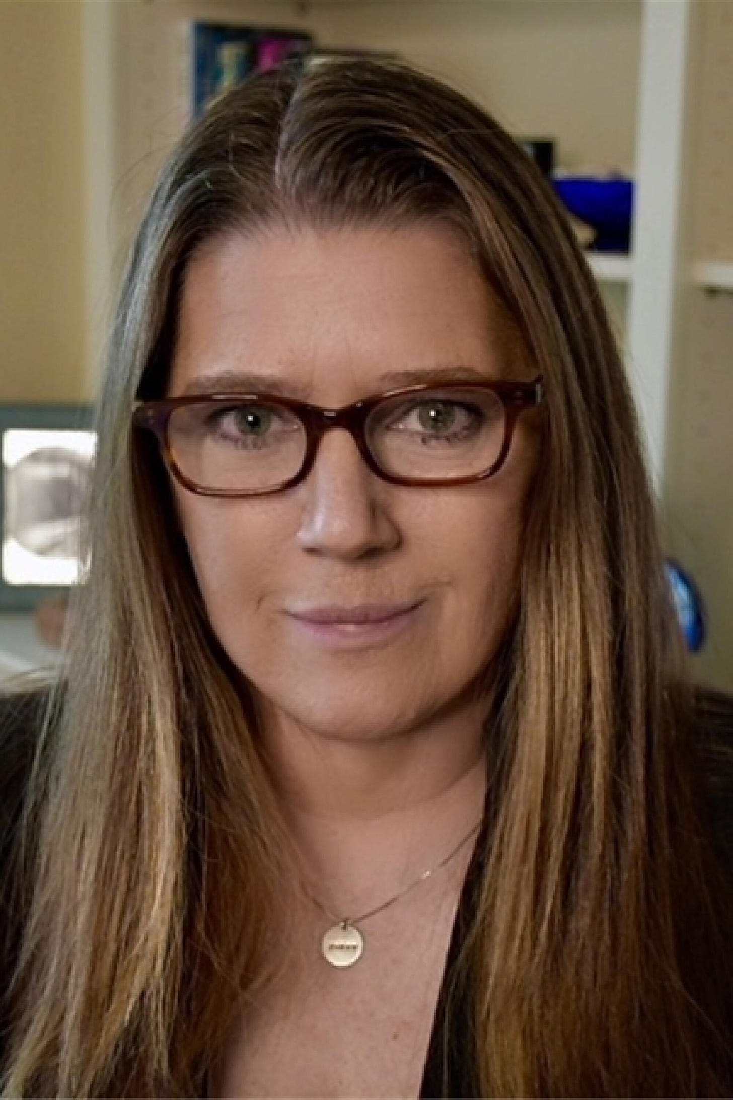 Portrait of a woman with long hair, glasses and a gold necklace