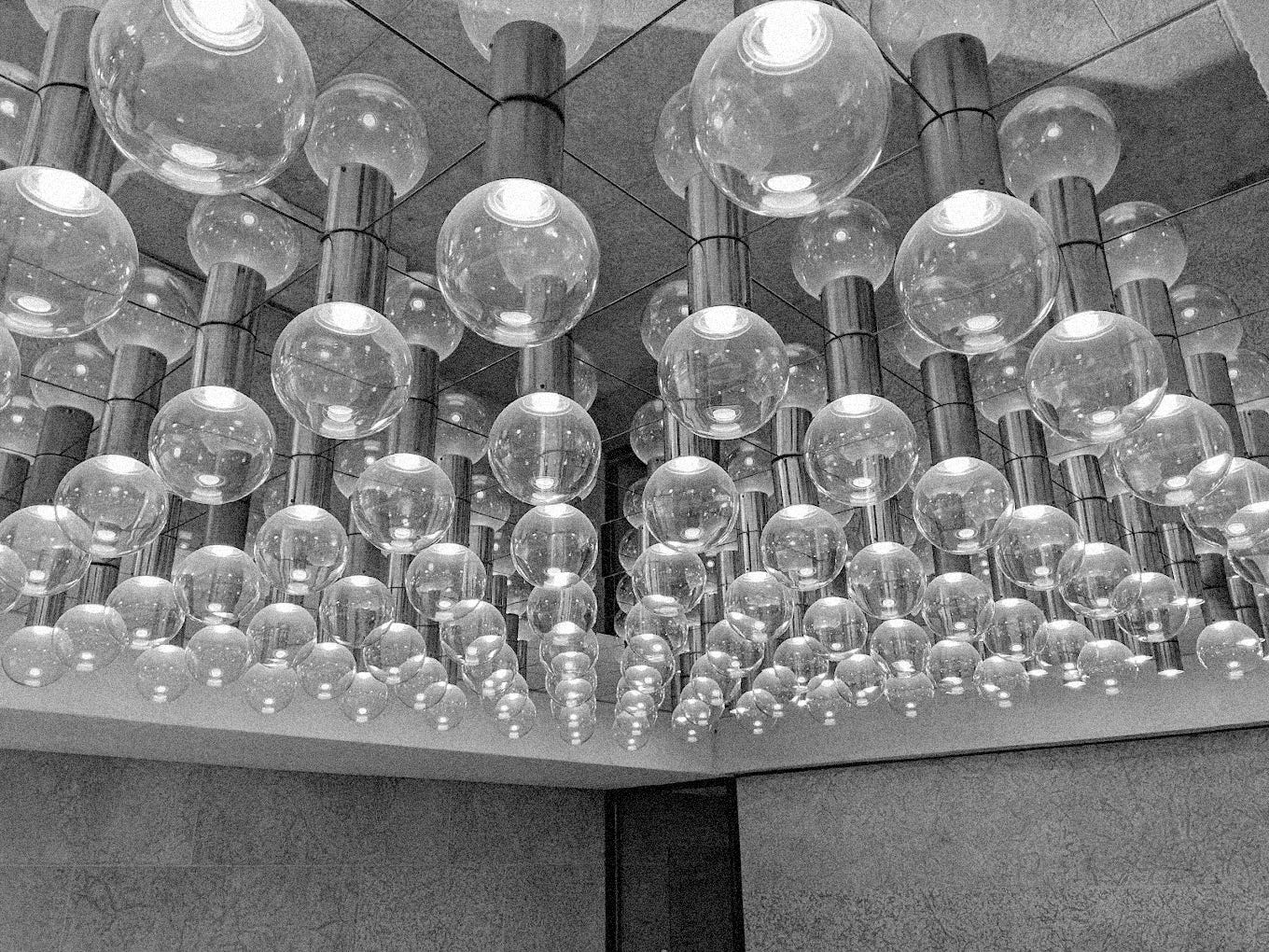 a black and white grainy photo of a mirrored ceiling with rows and rows of mounted lightbulbs 