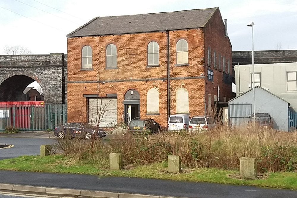 The Old Chapel Studio in Leeds, a renovated chapel with arched windows and a grassy area in front