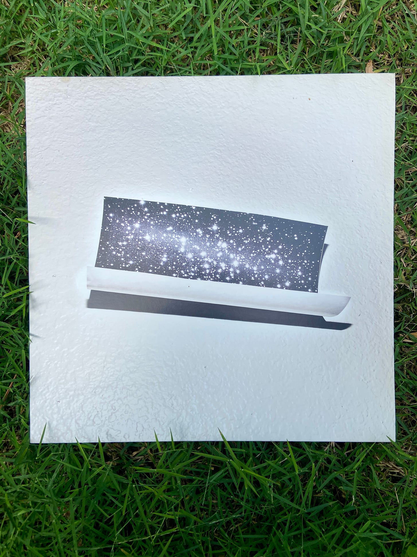 a vinyl of Bear in Heaven's fourth album Time is Over One Day Old sits on bright green grass. the album has a photo of constellations in the night sky against a textured white wall.