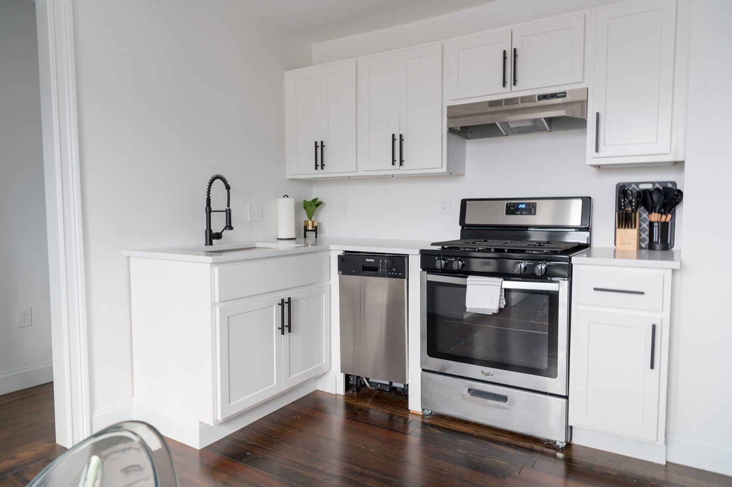 small kitchenette with an oven, a dishwasher, a sink, and minimal kitchen utensils