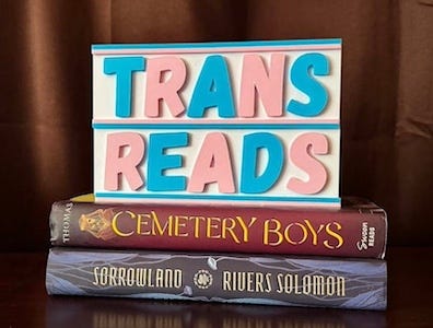 a sign that says trans reads in pink and blue letters