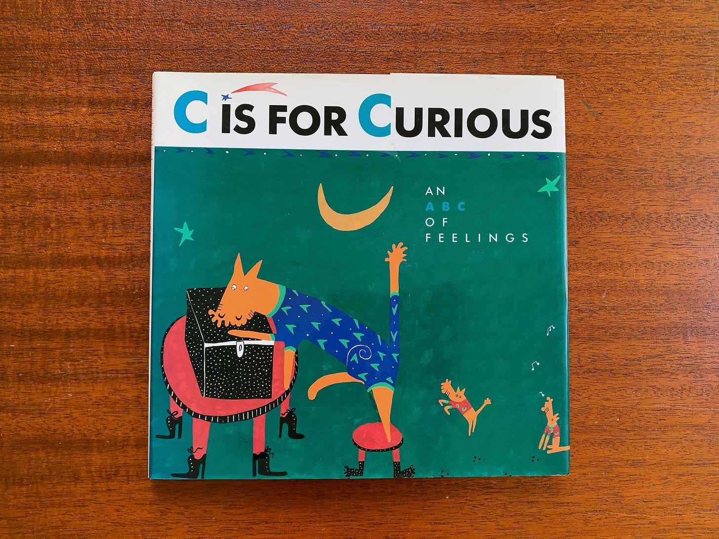 The front cover of "C is for Curious" which has a made up animal that looks like a fox peering into a box.