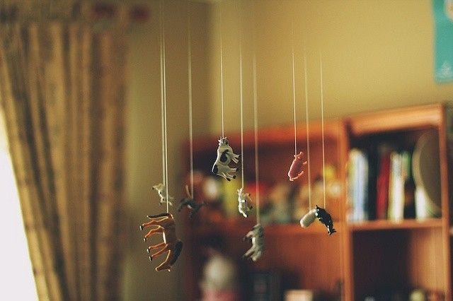 This may contain: there are many toy animals hanging from the strings in this room with bookshelves