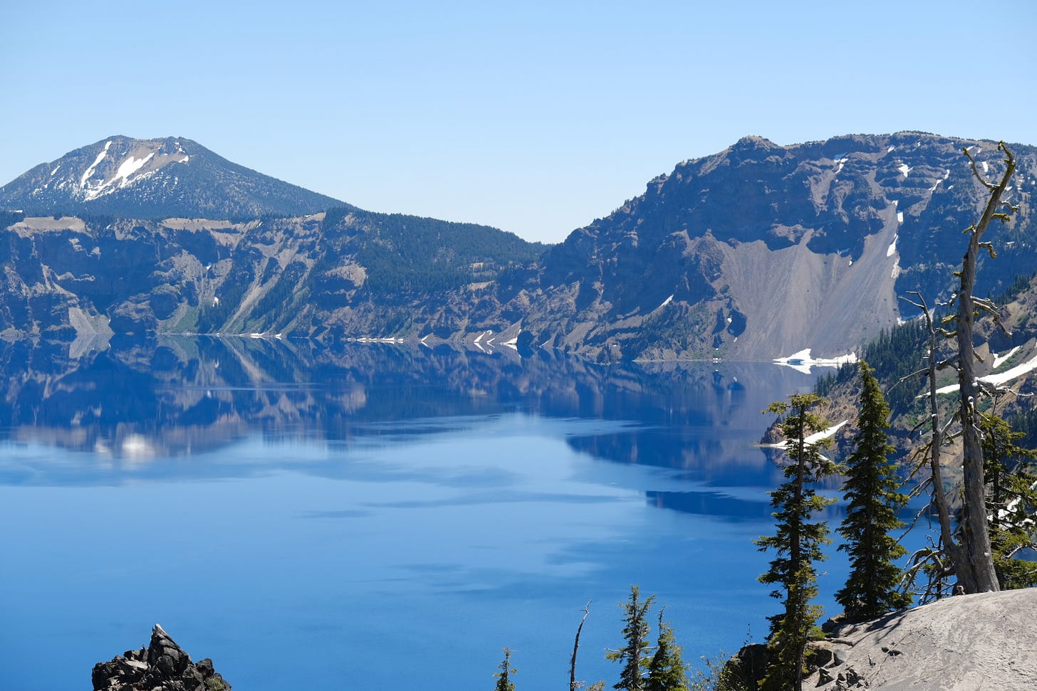 An image of blue skies and the rim of Crater lake reflected in the body of the lake.  rater lake