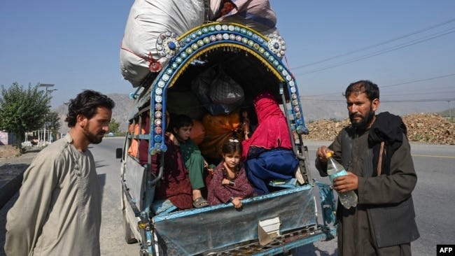 Afghan nationals along with their families stand along a road west of Peshawar, Pakistan, on October 6.