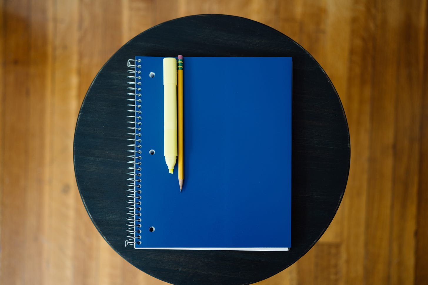 An arrangement of a spiral notebook, a pencil, and a highlighter.