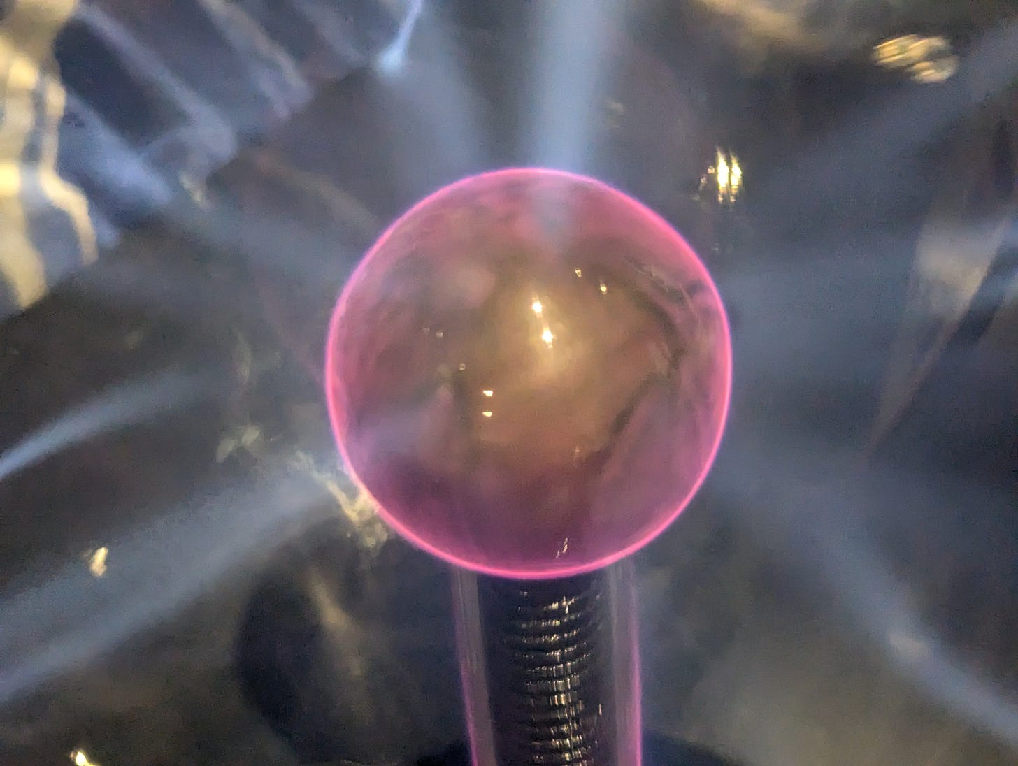 A tesla coil with a ball on one end, surrounded by red plasma.