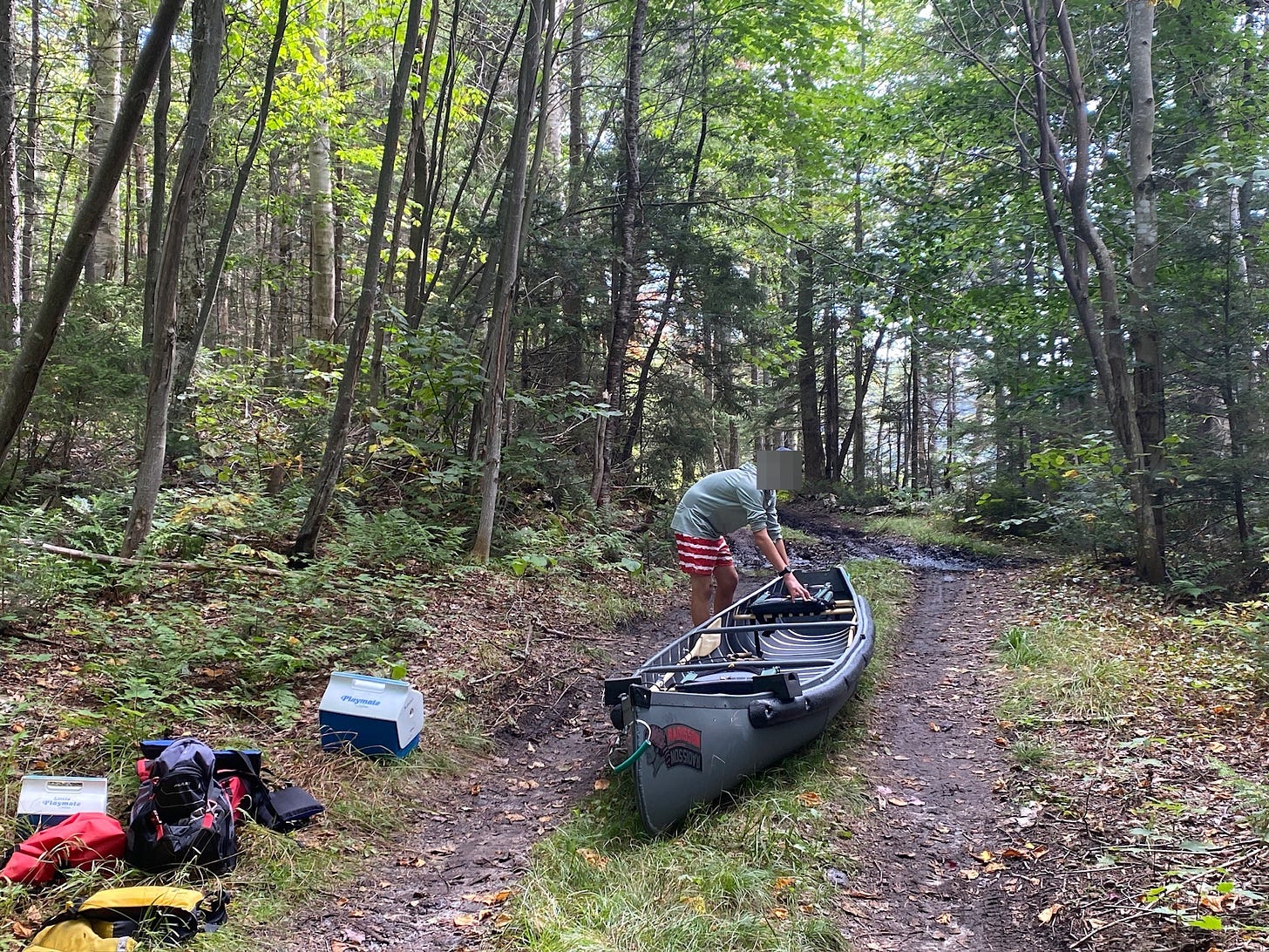 The Radisson canoe on a forest road with gear.