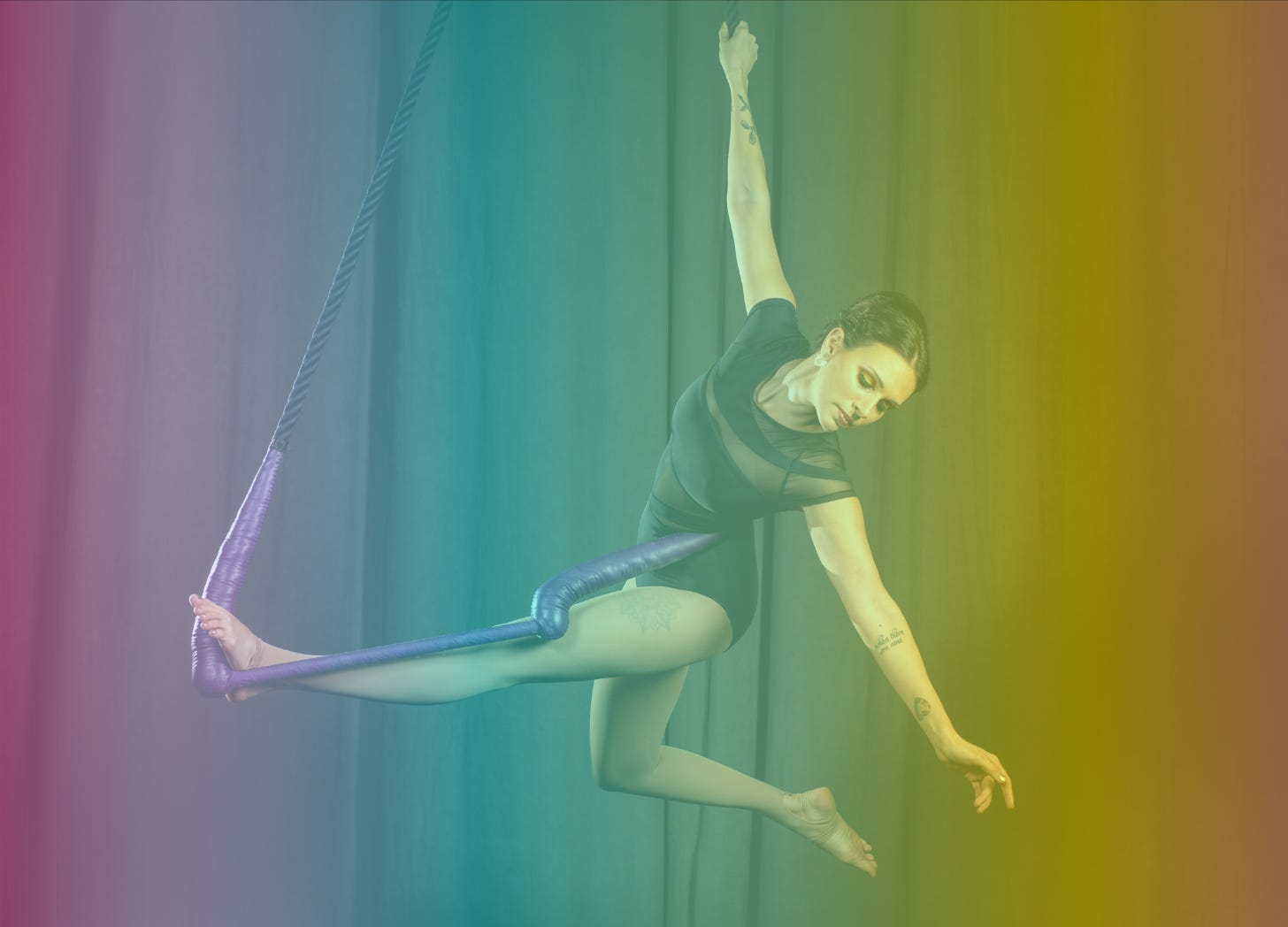 A rainbow-filtered photograph of Shohreh wearing a black leotard and doing a pose called Leanna on her purple trapeze