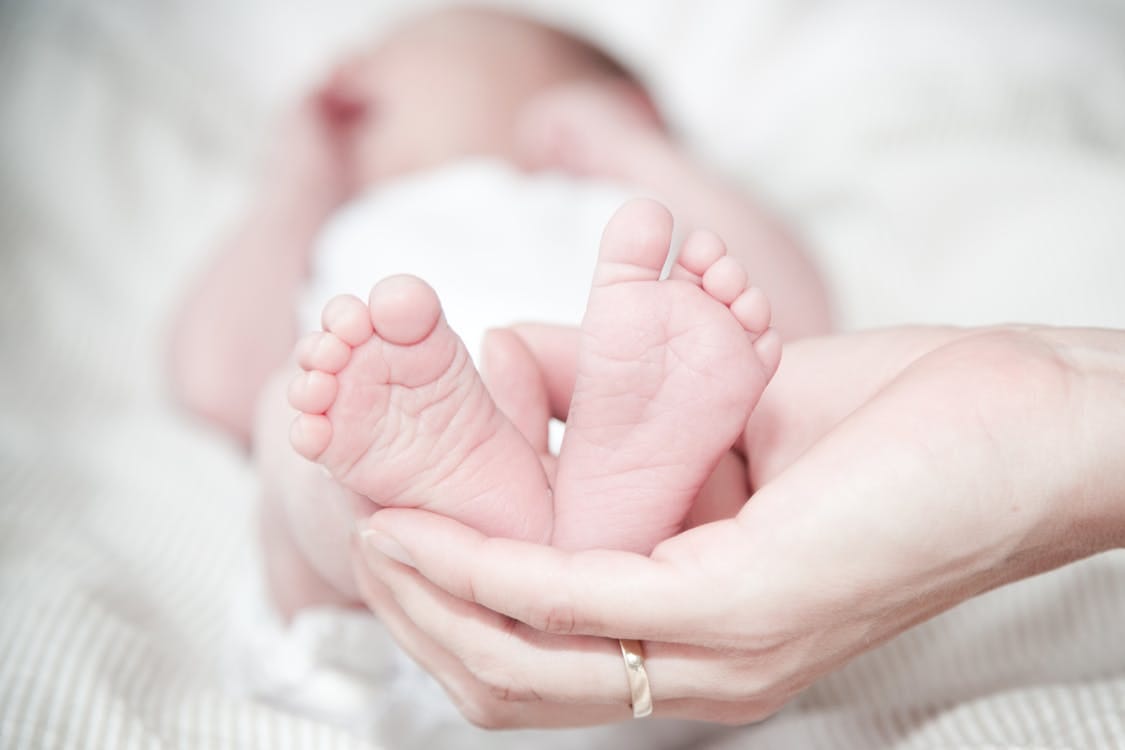 Free Tender photo of a mother's hands holding her newborn's feet, symbolizing love and care. Stock Photo