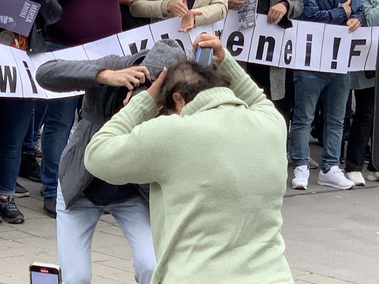 Foto: Sulzbacher: Als Zeichen der Verbundenheit, schneidet sich eine Frau ihre Haare bei einer Demo in Wien ab.