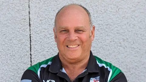 Chew Valley RFC Headshot of Steve Worrall smiling, standing against a white outside wall, wearing a Chew Valley RFC top