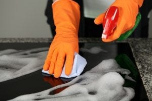 someone scrubbing their kitchen with orange rubber gloves on.