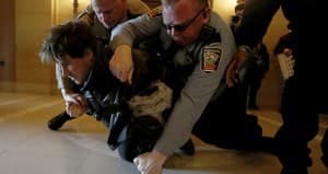 Two police officers wrestle a man wearing black to the ground. Two police officers wrestle a man wearing black to the ground.