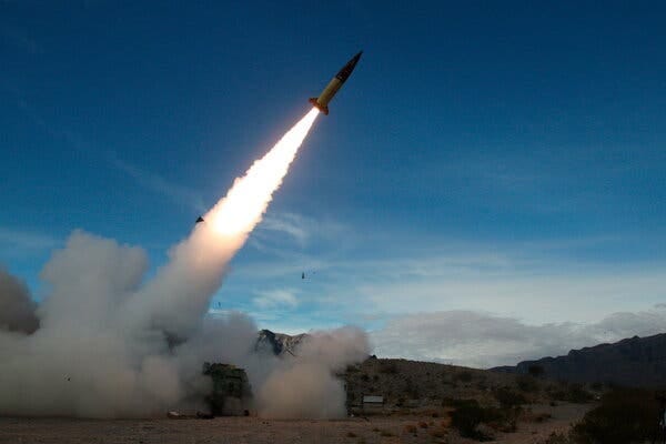 A missile is launched from the ground with a fiery trail across a blue sky.