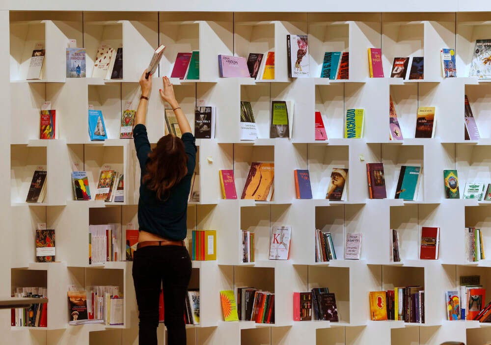 A woman puts books into a shelf. (Michael Probst/AP)