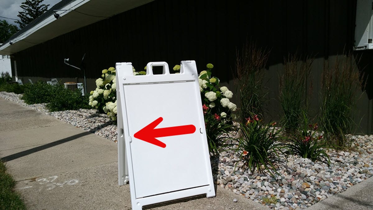 a-frame sign with an arrow pointing down the street