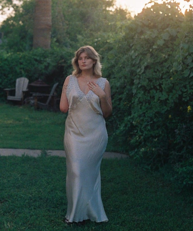 May include: A person wearing a white satin dress with lace trim.