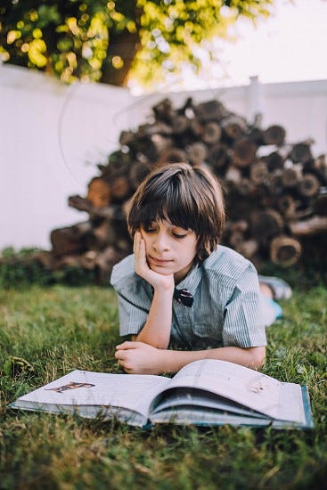 boy reading a book outside by Nina C. Photo stock - StudioNow