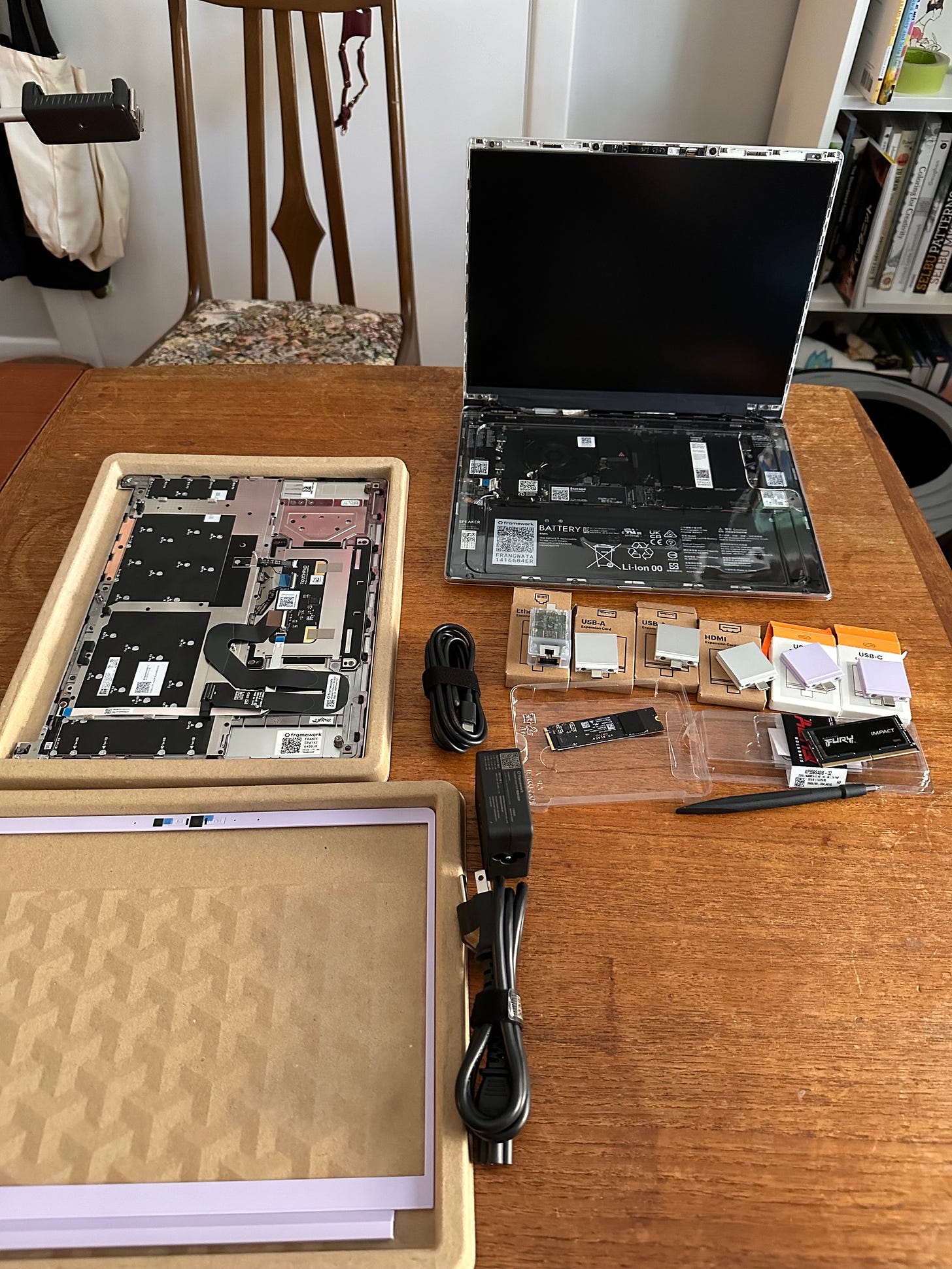 a wood table is covered in laptop components, ready for assembly.