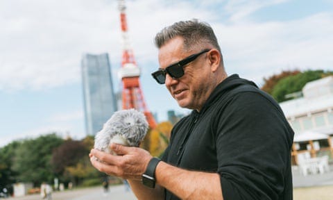 Justin McCurry at the Tokyo Tower with his Moflin, which squeaks when he strokes it