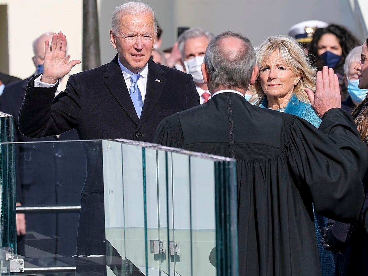 Joe Biden faces the Chief Justice John Roberts with his hand raised and Jill Biden at his side.