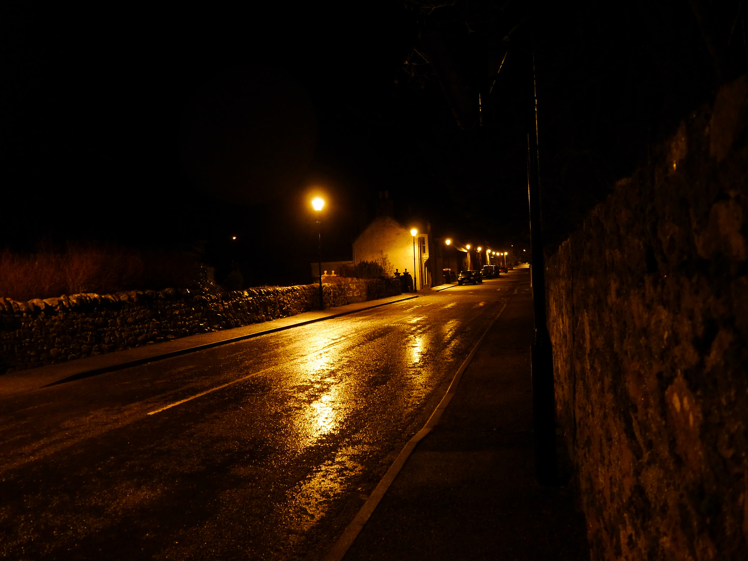 A dark street lit by orange streetlights