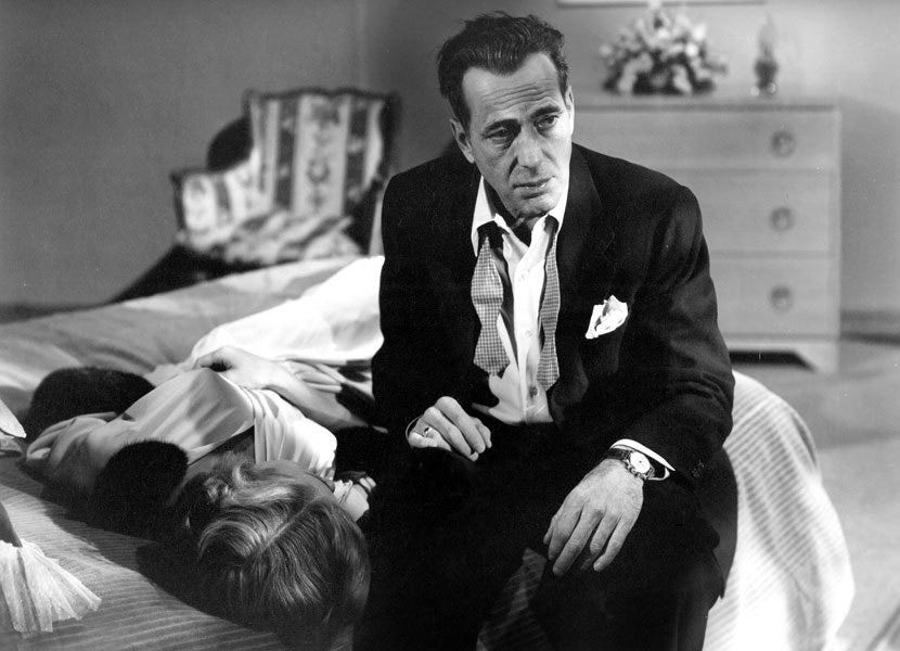 Humphrey Bogart sits on a bed next to the prone Gloria Grahame in "A Lonely Place" (1950)