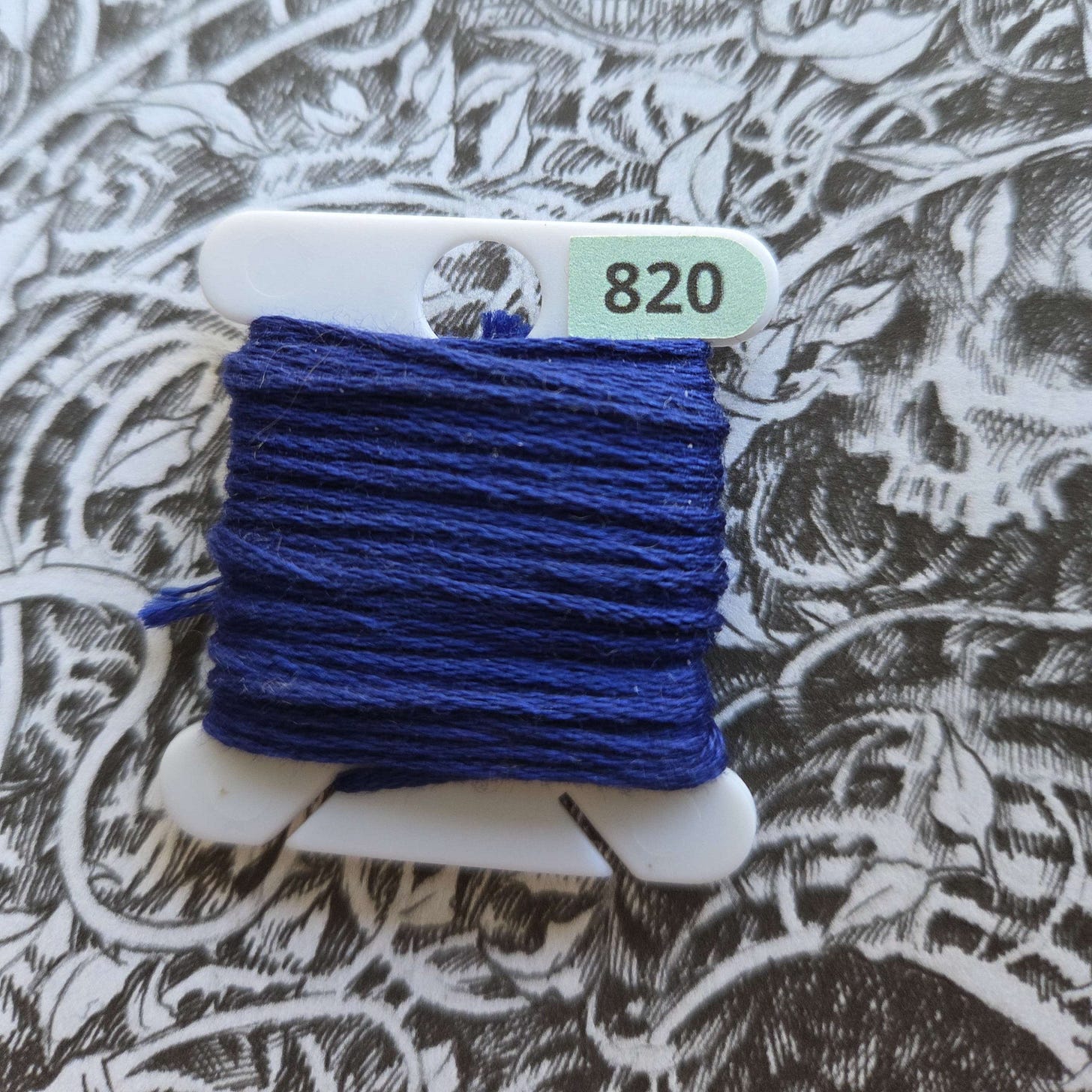 An embroidery bobbin with a bright blue floss wrapped around it.