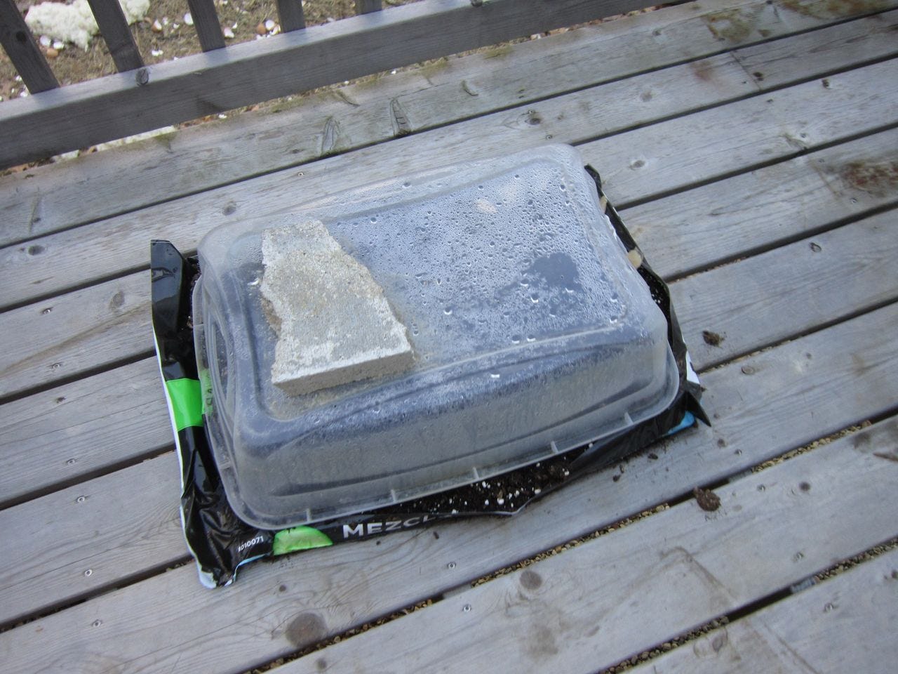 An experiment- a plastic container over a bag of potting soil.