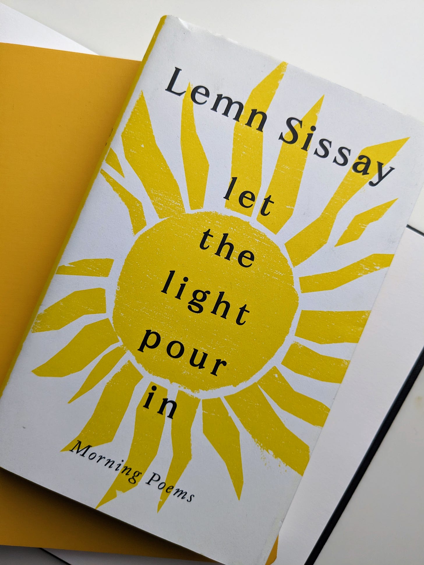 image of the book by Lemn Sissay: let the light pour in: morning poems. Bold yellow sun on white cover.