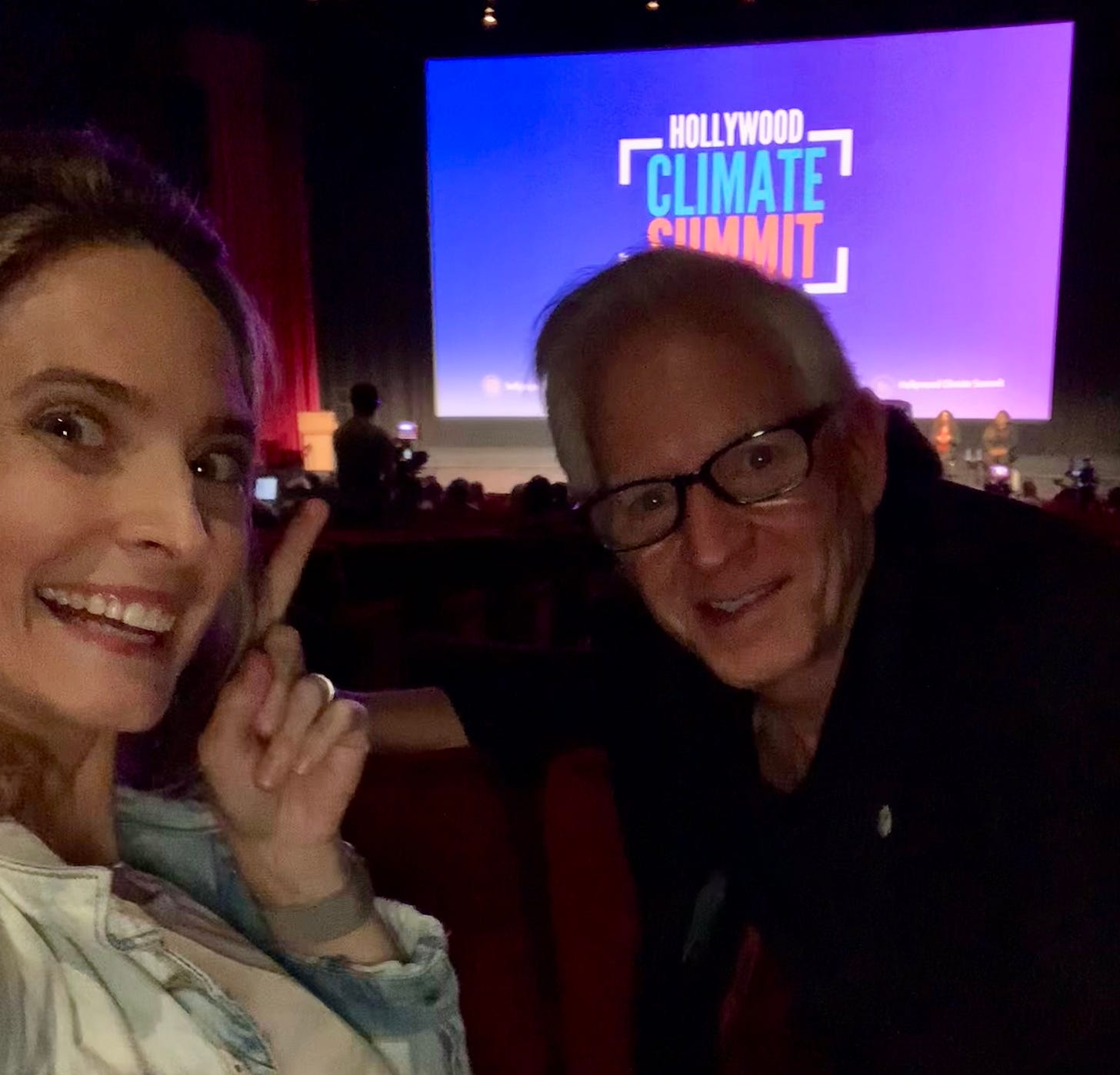 Gia and Jim in a theatre with a projection reading Hollywood Climate Summit projected behind the panelists