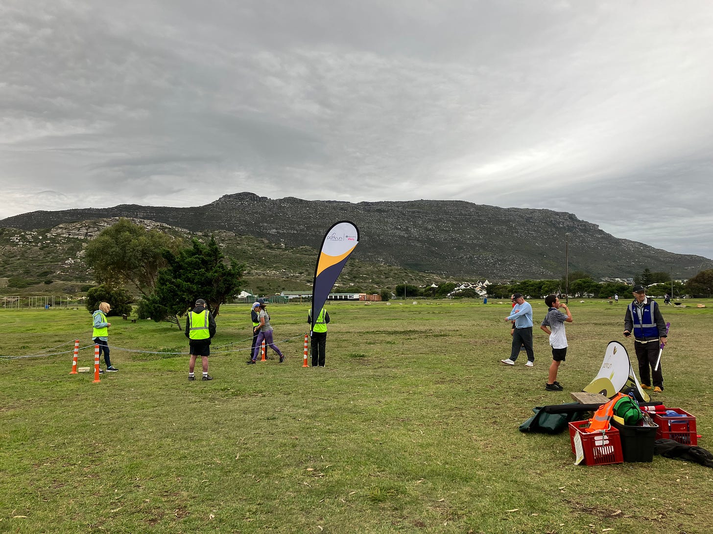 A parkrun flag, cones and rope mark the finish chute on grass looking onto mountains