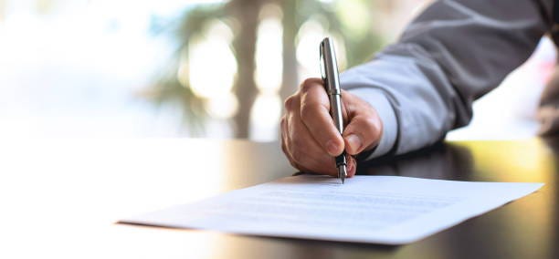 Signing Official Document Businessman Signing An Official Document pen and paper stock pictures, royalty-free photos & images