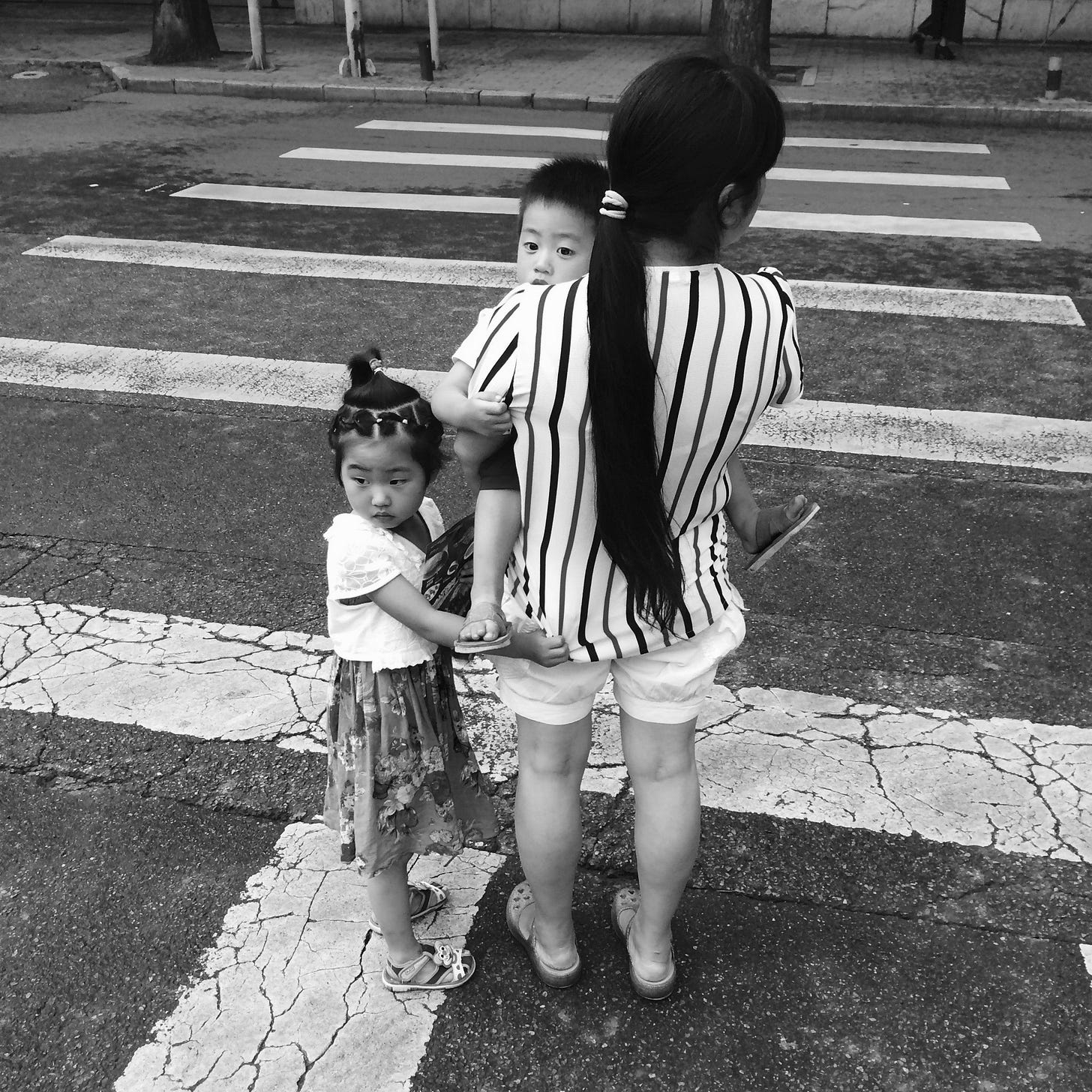 Mother and her children waiting to cross the road in Beijing.