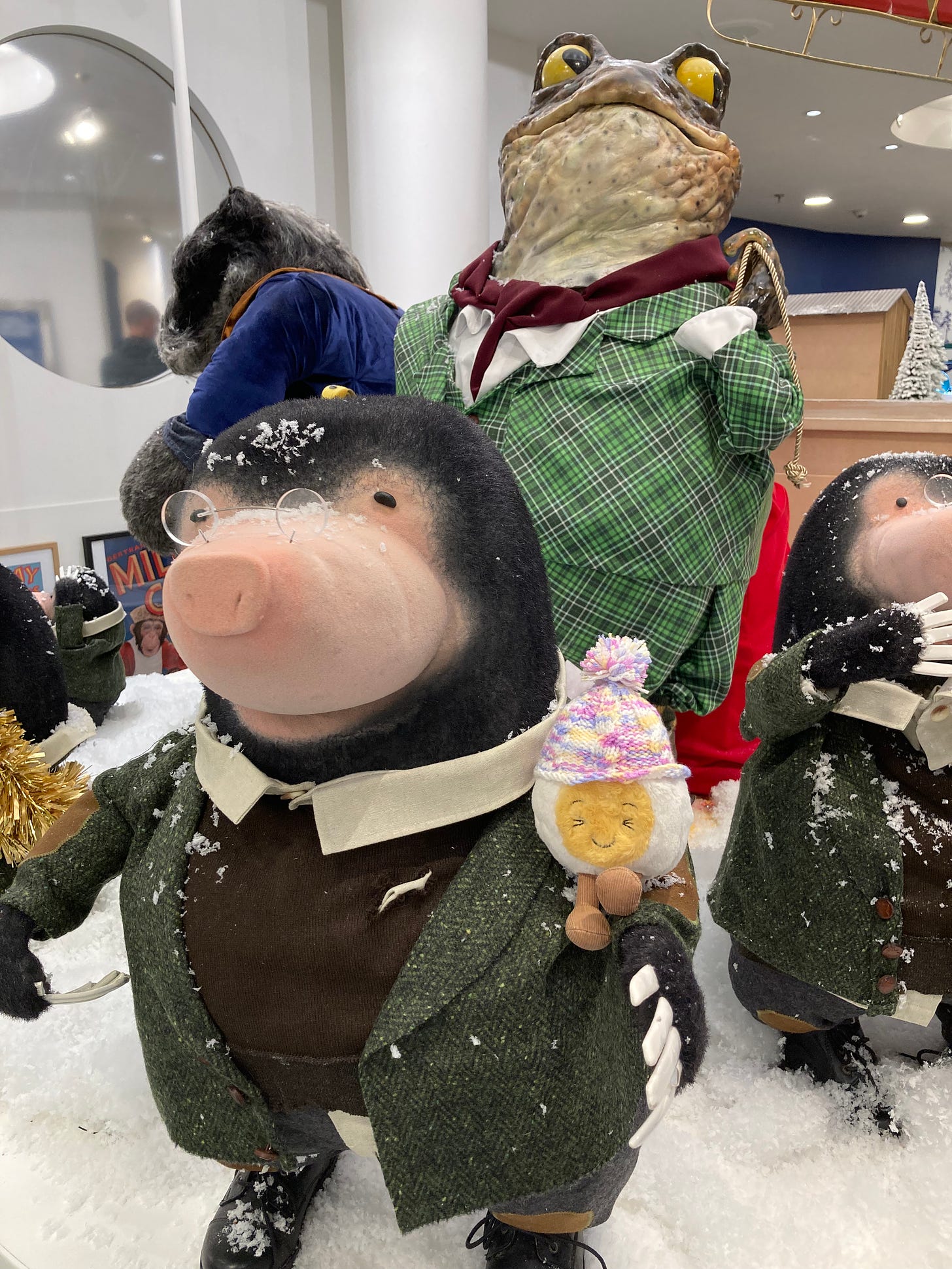 photograph of a mole statue from the book Wind in the Willows, dressed in dapper clothes and surrounded by snow. Dippy the soft toy egg is sitting on the mole's arm and wearing a tiny bobble hat knitted by my auntie