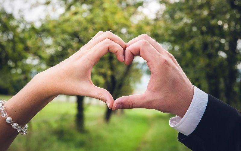 Woman and man holding their hands together in the shape of a heart.