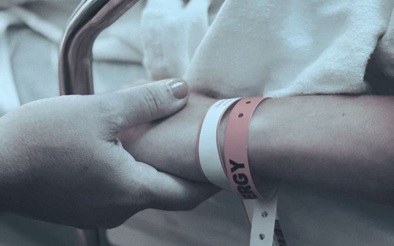 Mother's hand holding child's hand in hospital.