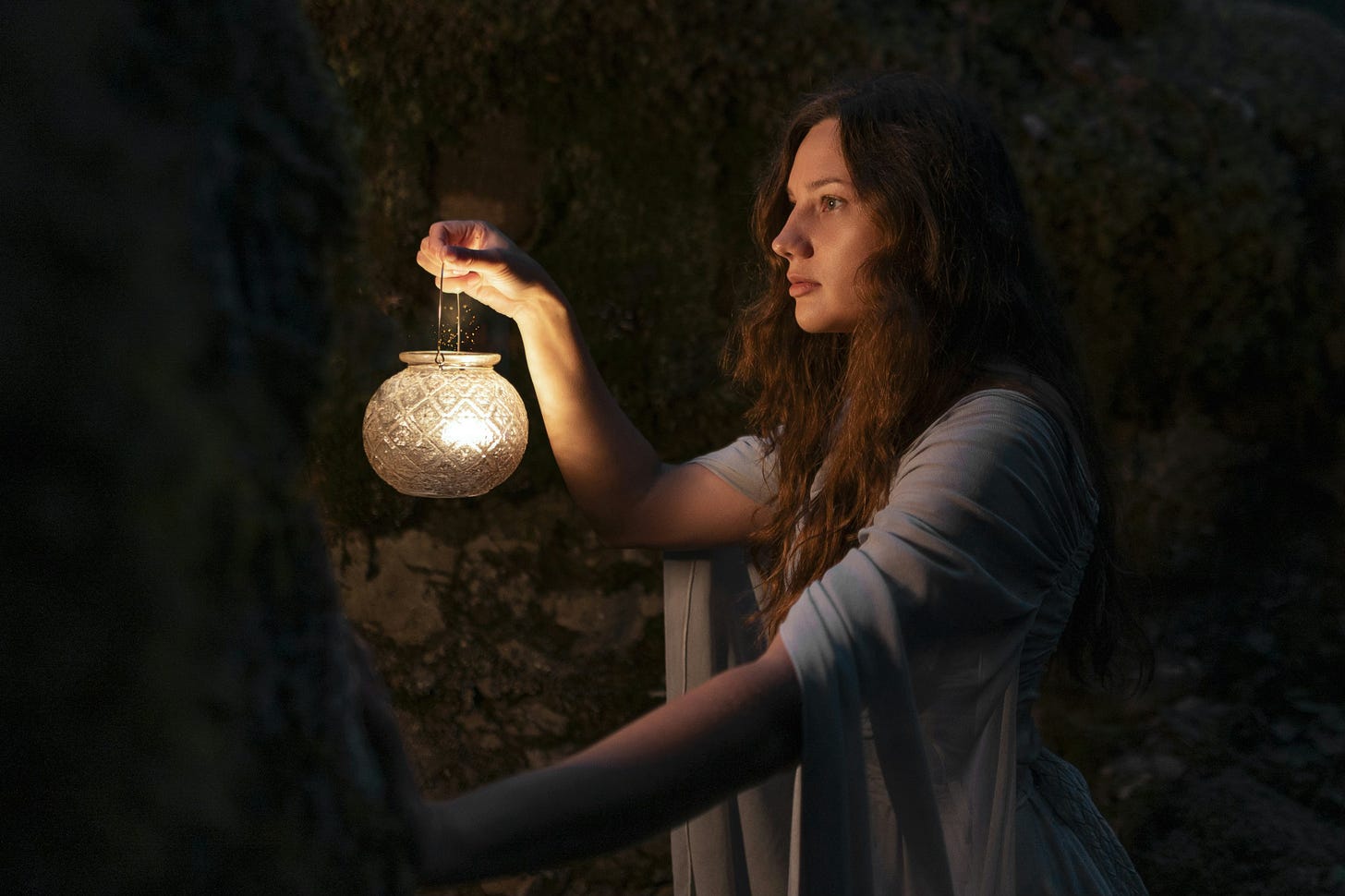 A woman holding a light in her hand to communicate the light of the self as one descends to their depths. A woman holding a light in her hand to communicate the light of the self as one descends to their depths.