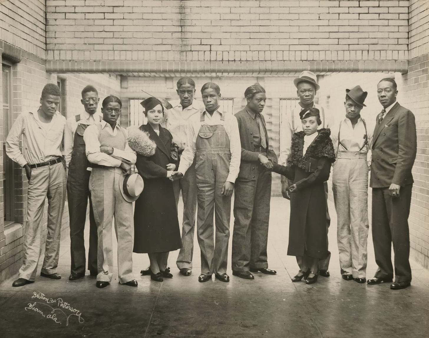 A photograph of young Black women activists Juanita Jackson Mitchell and Laura Kellum standing alongside the wrongly incarcerated Scottsboro Boys, a group of African American men. Mitchell and Kellum are dressed in formal attire, while the men are wearing working clothes.