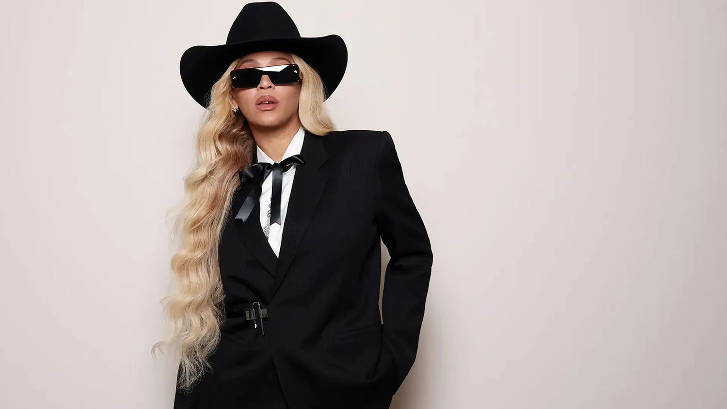 Picture of Beyoncé wearing a black suit, black sunglasses and black bolo tie