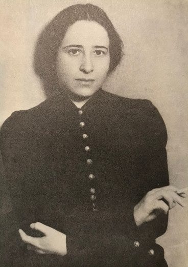 A portrait of Hannah Arendt, taken in 1933, in a black dress and smoking a cigarette.
