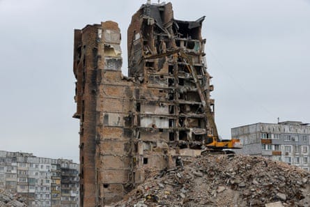 An excavator demolishes a block of flats.