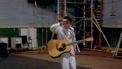 David Byrne in Stop Making Sense, stumbling around a stage with a guitar.