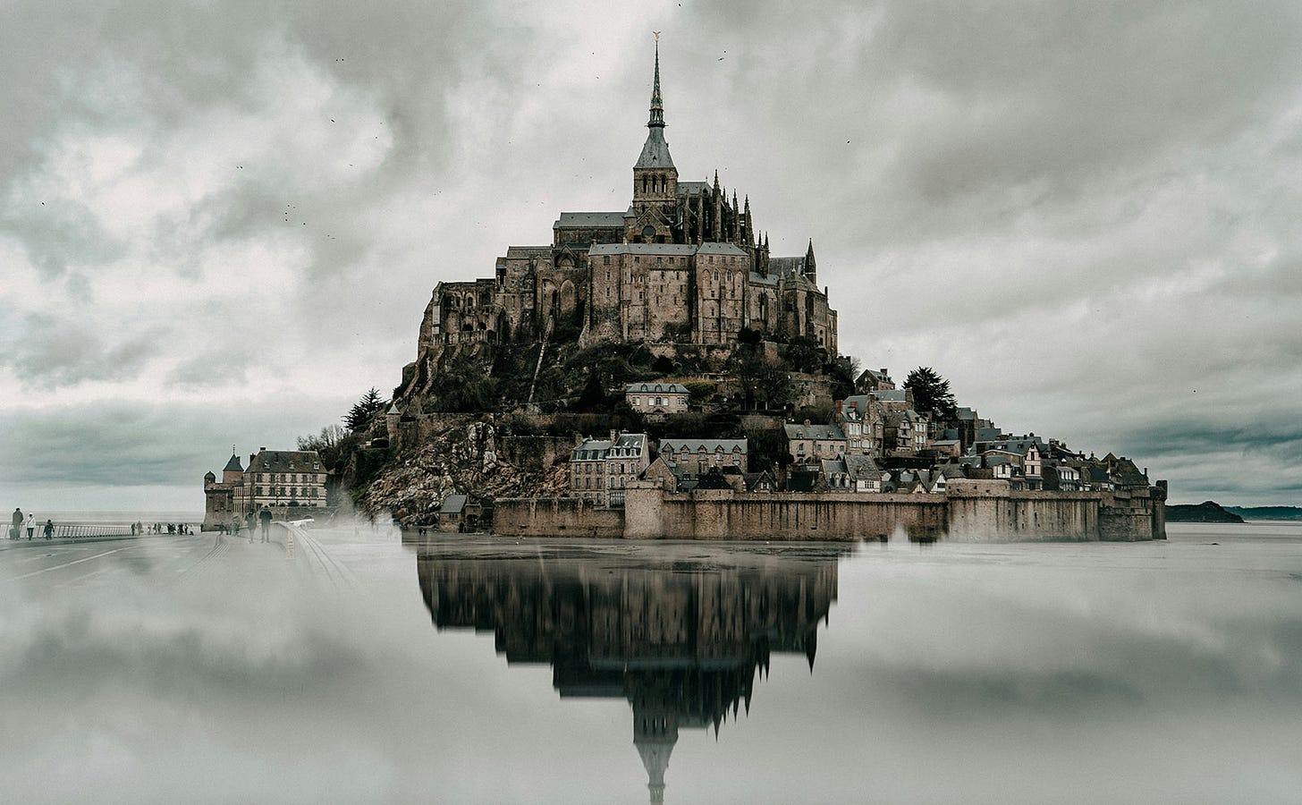 an island surrounded by calm water with a gothic church sitting on top of a hill