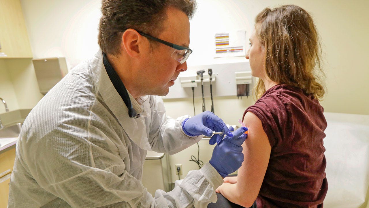 a pharmacist administers a vaccine to a patient