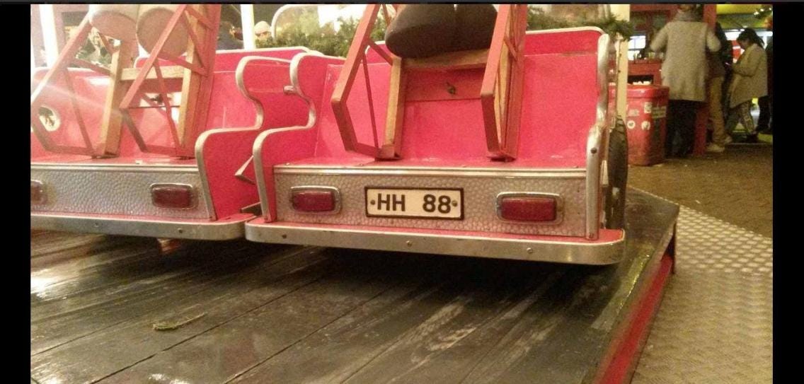 The rear of a small, red carousel car showing the numberplate, which reads ‘HH 88’