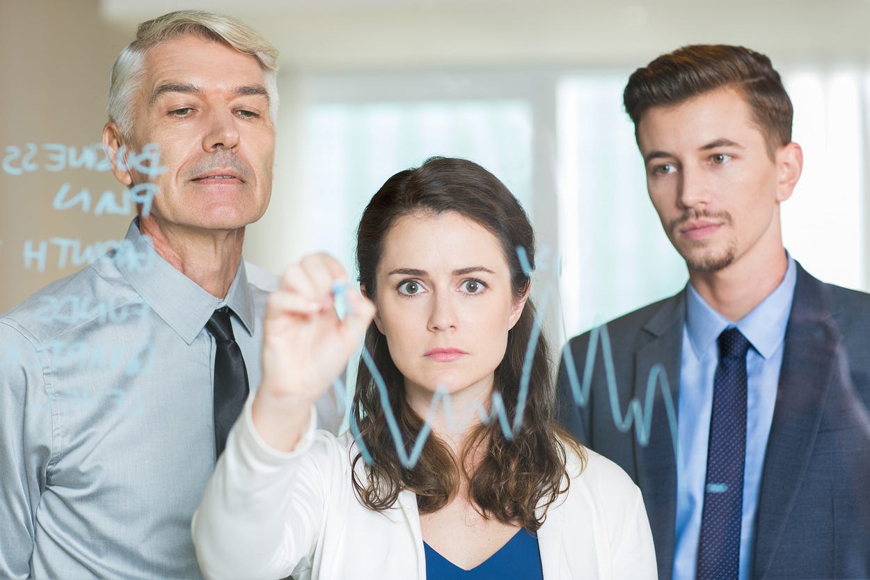 Businesswoman Drawing Graph on Glass Screen, two men watching her