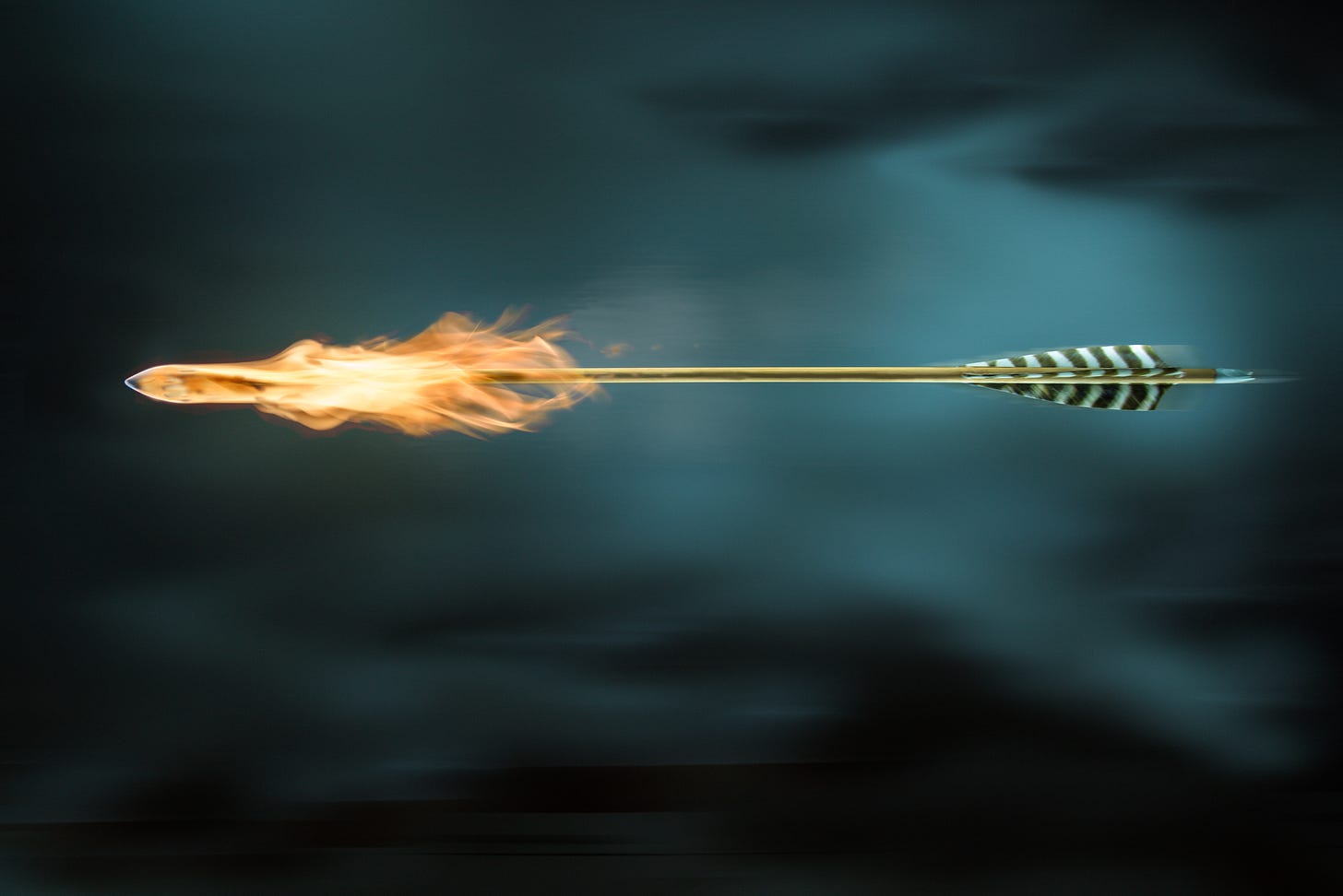 Picture of arrow with a flaming head against a dark clouded sky